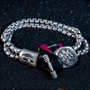 Silver bracelet with intricate designs on black.