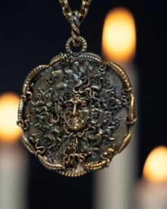 Ornate Medusa pendant with candlelight background.