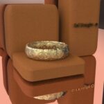 A gold ring sitting on top of a brown box.